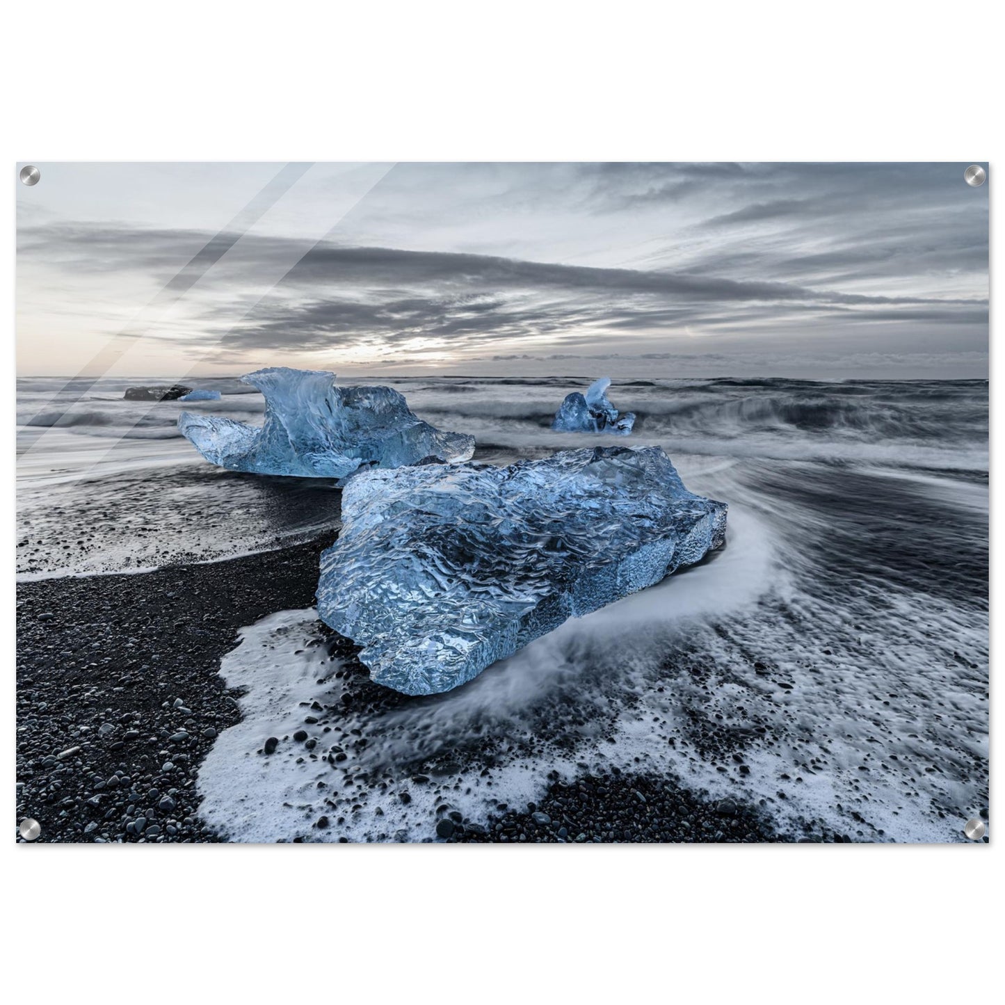 Landscape photography showcases the delicate harmony between blue ice and water, seamlessly intertwined with the dramatic black stones on the beach. Acrylic.