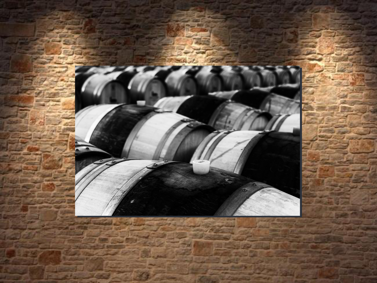 Black and white photo of wine barrels on a brick wall giving a beautiful voice and style to the wall.
