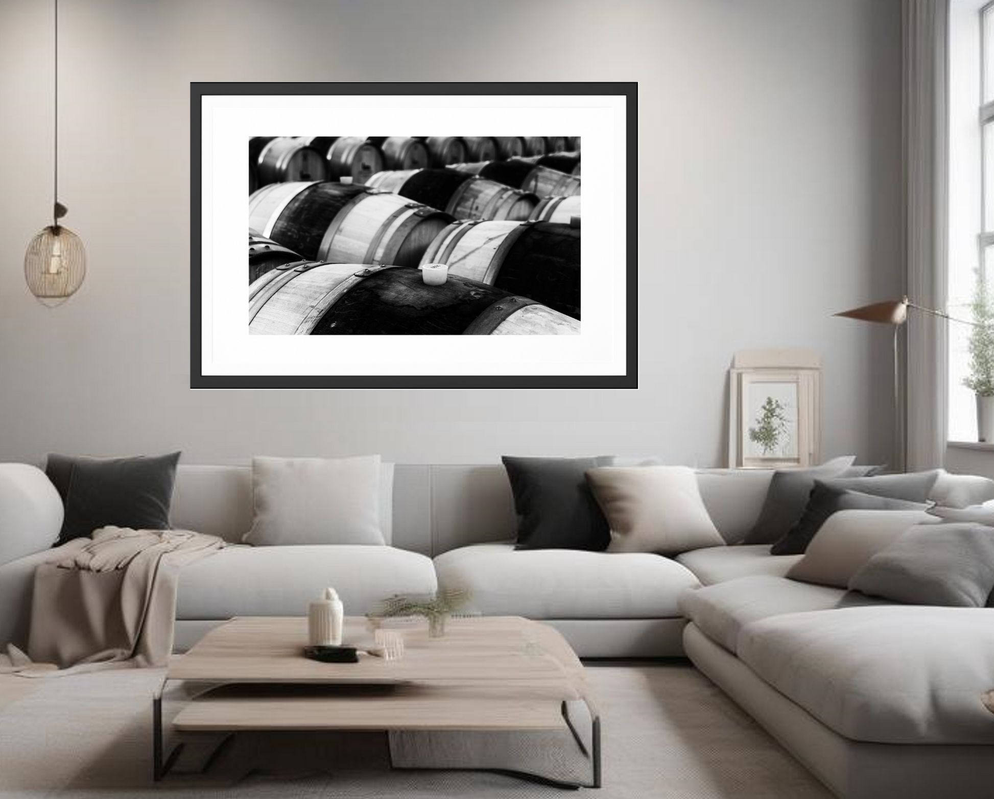 Framed black and white abstract art above a modern living room sofa. Row of wooden barrels with a white cap in the foreground. A stylish photography in black and white ideal for minimalistic modern or rustic spaces, an even for bohemian ones.