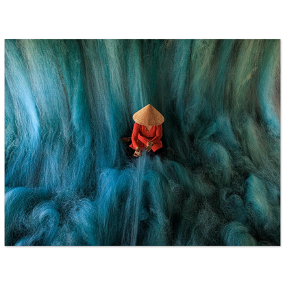 Fine art photo of a person in a conical hat mending blue fishing nets, resembling a soft waterfall flowing around them. Museum Quality printing materials.