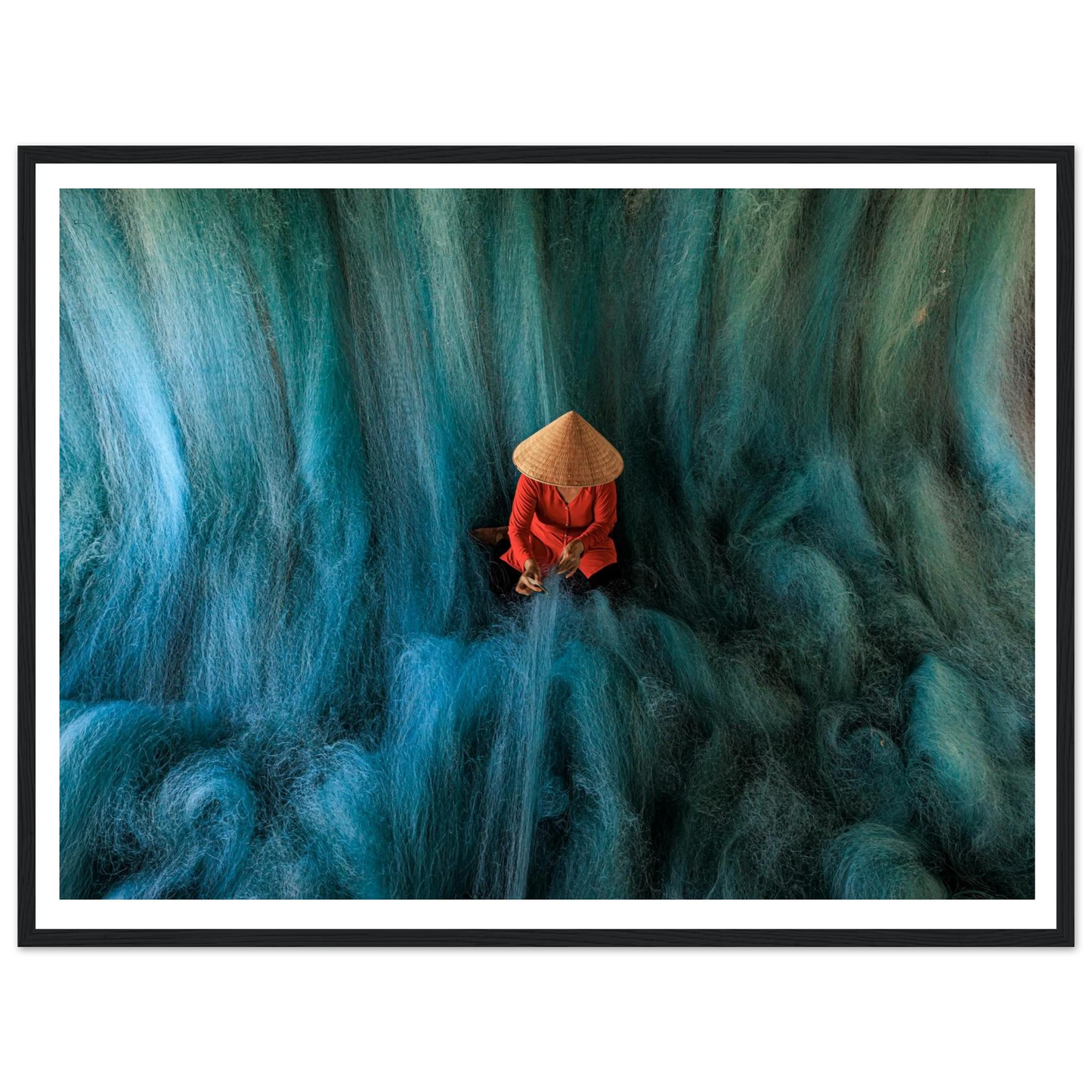 Person in a red outfit and straw hat sitting on a textured blue surface