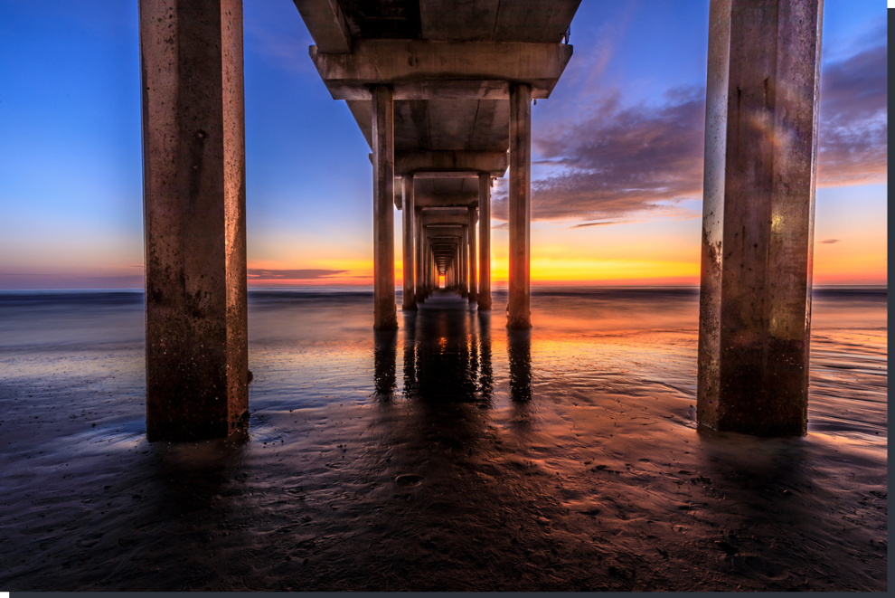 Sunset view under a pier with water reflections