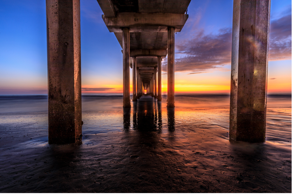 Sunset view under a pier with water reflections
