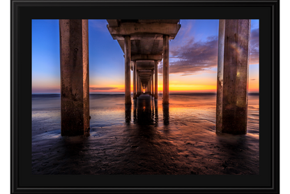 Sunset view under a pier with columns and water reflection