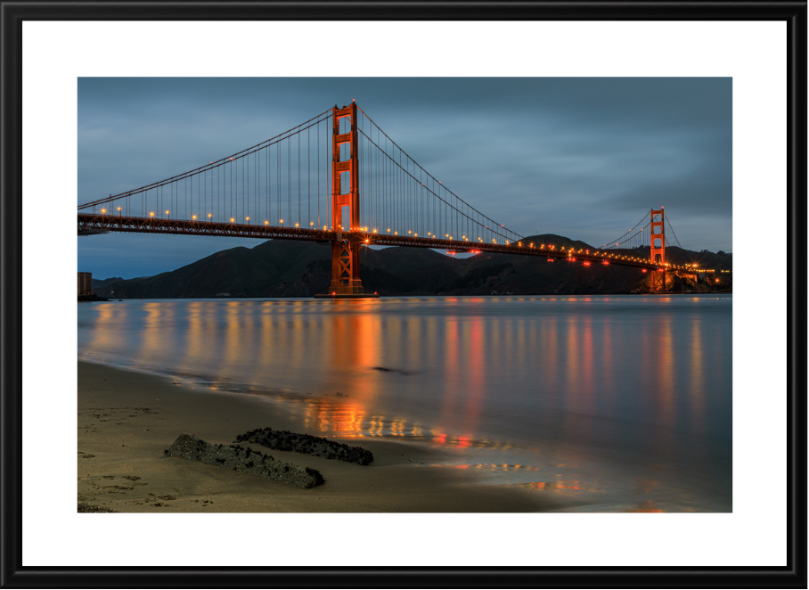 Framed photograph of the Golden Gate Bridge at dusk with reflection on water.